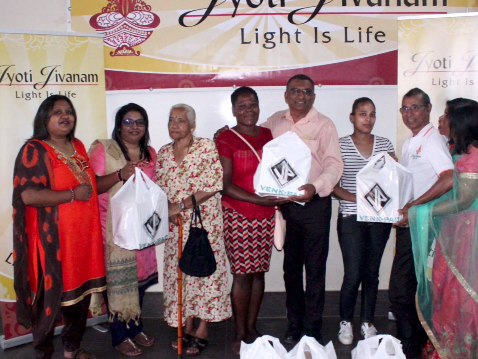 Families receiving Jyoti Jivanam food hampers in front of the movement banners